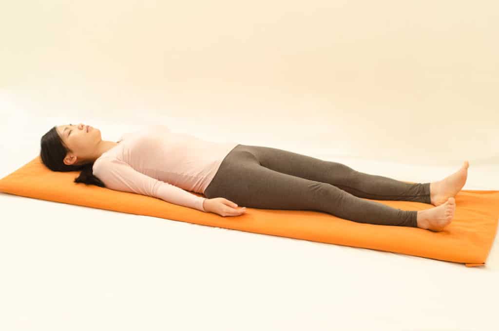 Woman lying on her back in savasana. 