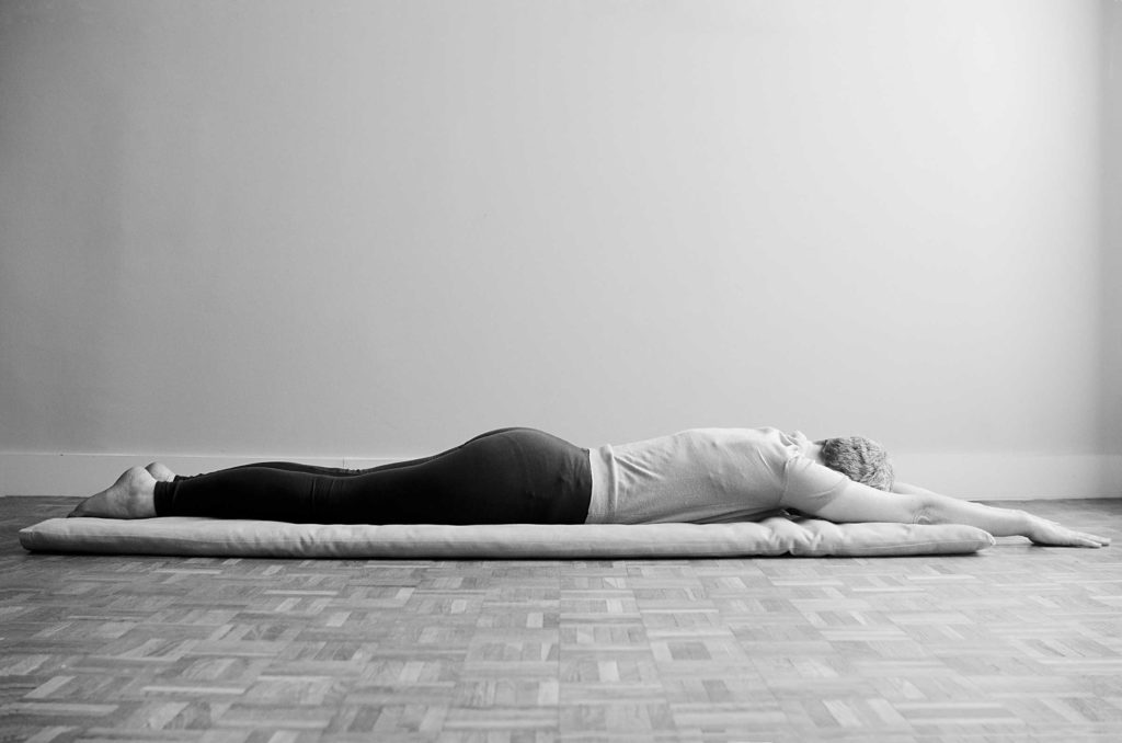 Woman in Advasana. Shavasana replacement done lying flat on the belly.